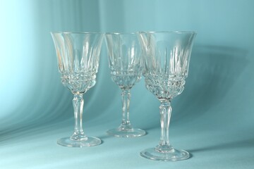 Empty wine glasses casting beautiful shadows on light blue background