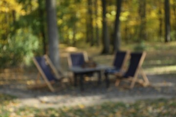 Naklejka premium Blurred view of beautiful autumnal park with picnic table and chairs