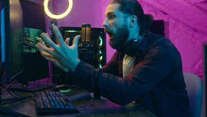 Addicted angry Caucasian guy streamer blogger vlogger influencer man playing online virtual game...