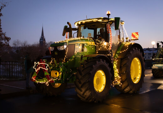 John Deere R6 bei der Lichterfahrt in Rinteln mit Weihnachtsbeleuchtung bei der Vorbeifahrt mit Weihnachtsdekoration, ein Funken Hoffnung in der Abendd&auml;mmerung
