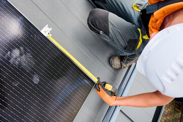 Worker building solar panel system on rooftop of house for generating electricity through...