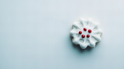 Delicate snowflake cookie with white icing and red sprinkles captured on a light background