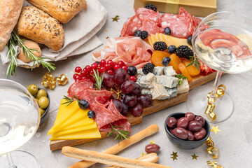 Italian food antipasti prosciutto ham, salami, olives and grissini bread sticks. cheese on a board parmesan, pecorino, gorgonzola. Charcuterie board. Two glasses of white wine or prosecco