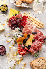 Italian food antipasti prosciutto ham, salami, olives and grissini bread sticks. cheese on a board parmesan, pecorino, gorgonzola. Charcuterie board. Two glasses of white wine or prosecco