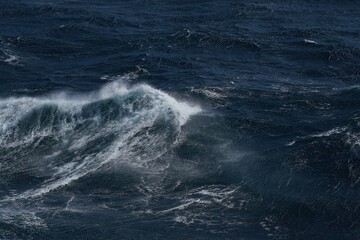 powerful ocean wave crashing in deep blue waters, showcasing raw beauty of nature. dynamic movement evokes sense of energy and tranquility