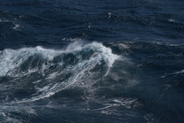 Majestic ocean waves crashing against each other, creating dynamic and powerful scene. deep blue water reflects energy of sea, evoking sense of awe and tranquility