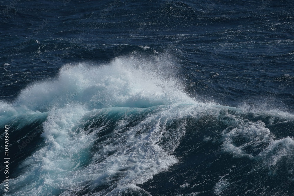 Wall mural dynamic ocean waves crashing with white foam against deep blue sea, creating sense of power and tran