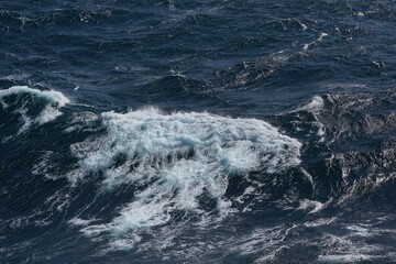 image captures dynamic movement of ocean waves, showcasing deep blue water and frothy white crests. scene evokes sense of tranquility and power of nature