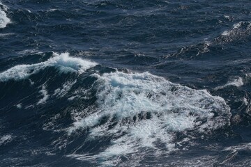 Fototapeta premium Waves crashing on deep blue ocean surface create dynamic and powerful scene. movement of water showcases beauty and energy of nature
