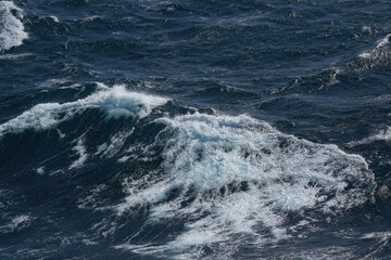 Waves crashing on ocean surface, creating dynamic and powerful scene. deep blue water contrasts with white foam, evoking sense of nature strength and beauty