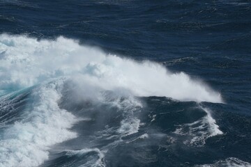 Powerful ocean waves crashing against each other, creating dramatic scene of white foam and deep blue water, showcasing beauty and force of nature
