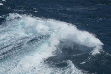 Powerful ocean waves crashing against each other create dramatic scene of nature force and beauty. deep blue water contrasts with white foam
