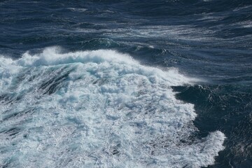 image captures dynamic movement of ocean waves, showcasing vibrant blue hues and frothy white crests. scene evokes sense of tranquility and power of nature
