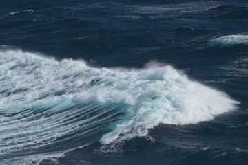 Majestic ocean waves crashing against each other, creating dynamic and powerful scene. deep blue water contrasts beautifully with white foam, evoking sense of tranquility and strength