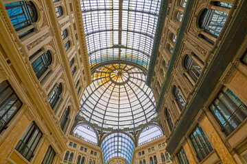 The photo features the stunning Umberto I Gallery in Naples, highlighting its elegant glass dome, intricate architecture, and bustling atmosphere.