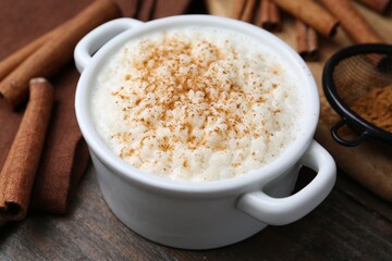 Delicious rice pudding with cinnamon on wooden table, closeup