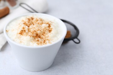 Delicious rice pudding with cinnamon on light table, closeup. Space for text