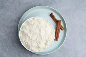 Delicious rice pudding with cinnamon sticks on grey table, top view