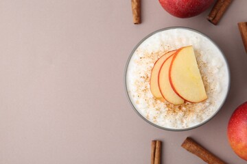 Delicious rice pudding with apples and cinnamon on color background, flat lay. Space for text