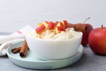 Delicious rice pudding with apples and cinnamon on grey table