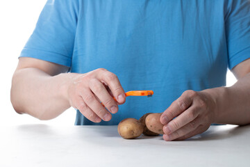 A vegetable peeler. A man cleans vegetables with a peeler.
