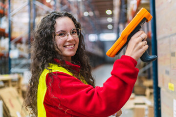 Warehouse young woman worker scanning packages with barcode scanner