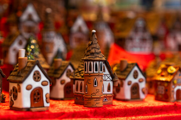 Fototapeta premium Detailed ceramic miniature houses and tower, arranged on red cloth display, creating cozy and festive village scene