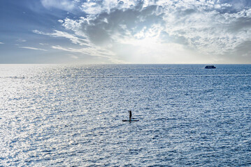 Obraz premium Silhouette of a woman practicing paddle surfing in the sea of ​​Menorca at sunset. Balearic Islands 