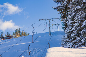 Snow-covered ski lift equipment under a clear blue sky, capturing the essence of winter sports and...