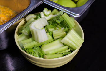 Fresh green celery sticks arranged in a yellow bowl ready for a healthy snack.