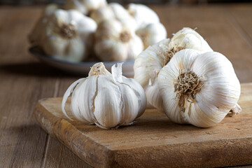 Fresh organic garlic bulbs on wooden cutting board. Close up.