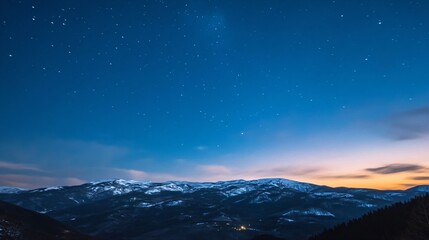 Stunning winter mountain landscape at dusk with snow-capped peaks under starry blue sky. Panoramic evening vista of mountain range with sunset glow. Nature scenery for travel and outdoor