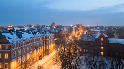 Obraz premium Winter evening cityscape with snow covered rooftops in historic European town. Old architecture illuminated by warm street lights. Urban twilight panorama with golden glow