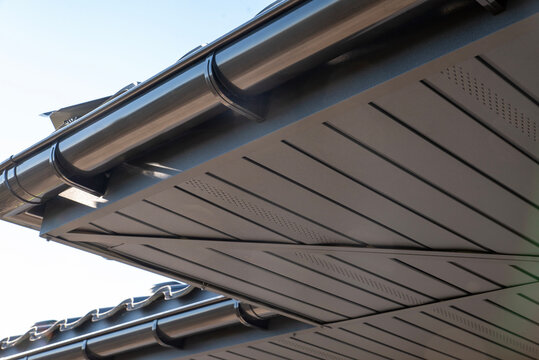 Gray perforated metal soffit on a house with gutter system