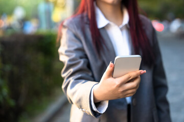 Female business office worker holding phone, outdoors