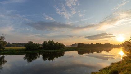 Fototapeta premium Calm river with a beautiful sunset in the background