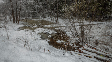 Snowy landscape with a stream of water running through it