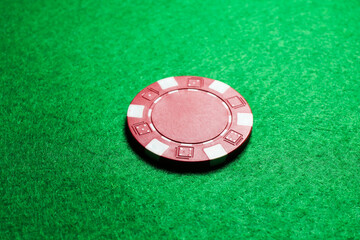 One poker chip on green table, closeup