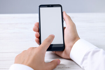 Man unlocking smartphone with fingerprint scanner at light wooden table, closeup