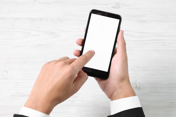 Man unlocking smartphone with fingerprint scanner at light wooden table, top view