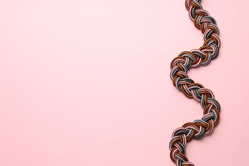 Braided colorful ropes on light pink background, top view with space for text. Unity concept