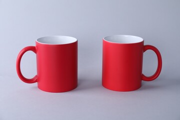 Two blank red mugs on light background. Mockup for design