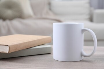 Blank ceramic mug and notebooks on wooden table. Mockup for design