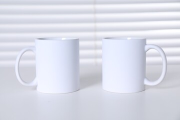 Obraz premium Blank ceramic mugs on white table. Mockup for design