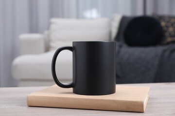 Blank black ceramic mug and notebook on wooden table. Mockup for design
