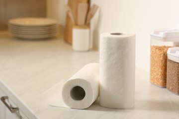 Rolls of paper towels on white countertop in kitchen, space for text