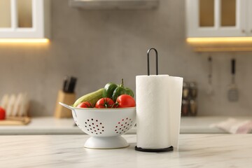 Roll of paper towels and vegetables on white marble table in kitchen