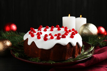 Tasty Christmas cake with red currants and rosemary on black wooden table, closeup