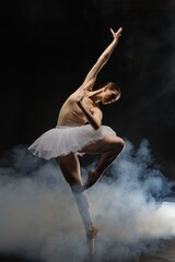 Dancer performing an elegant ballet pose amidst dramatic smoke effects