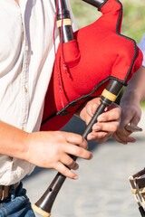 detail of the hands of a bagpipe player playing a traditional red bagpipe from Portugal, background concept folk music